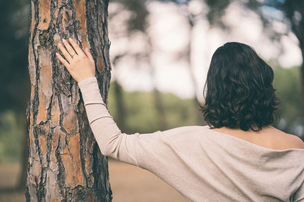 Una mano humana interactuando sutilmente con un elemento de la naturaleza (rozando la corteza de un árbol, sosteniendo agua, o tocando hojas tiernas), o bien dos texturas orgánicas distintas que encajan de forma armónica sin mezclarse. Transmite la idea de que la comunicación y la identidad autista son formas naturales e inherentes de estar en el mundo, alejándose de la patologización